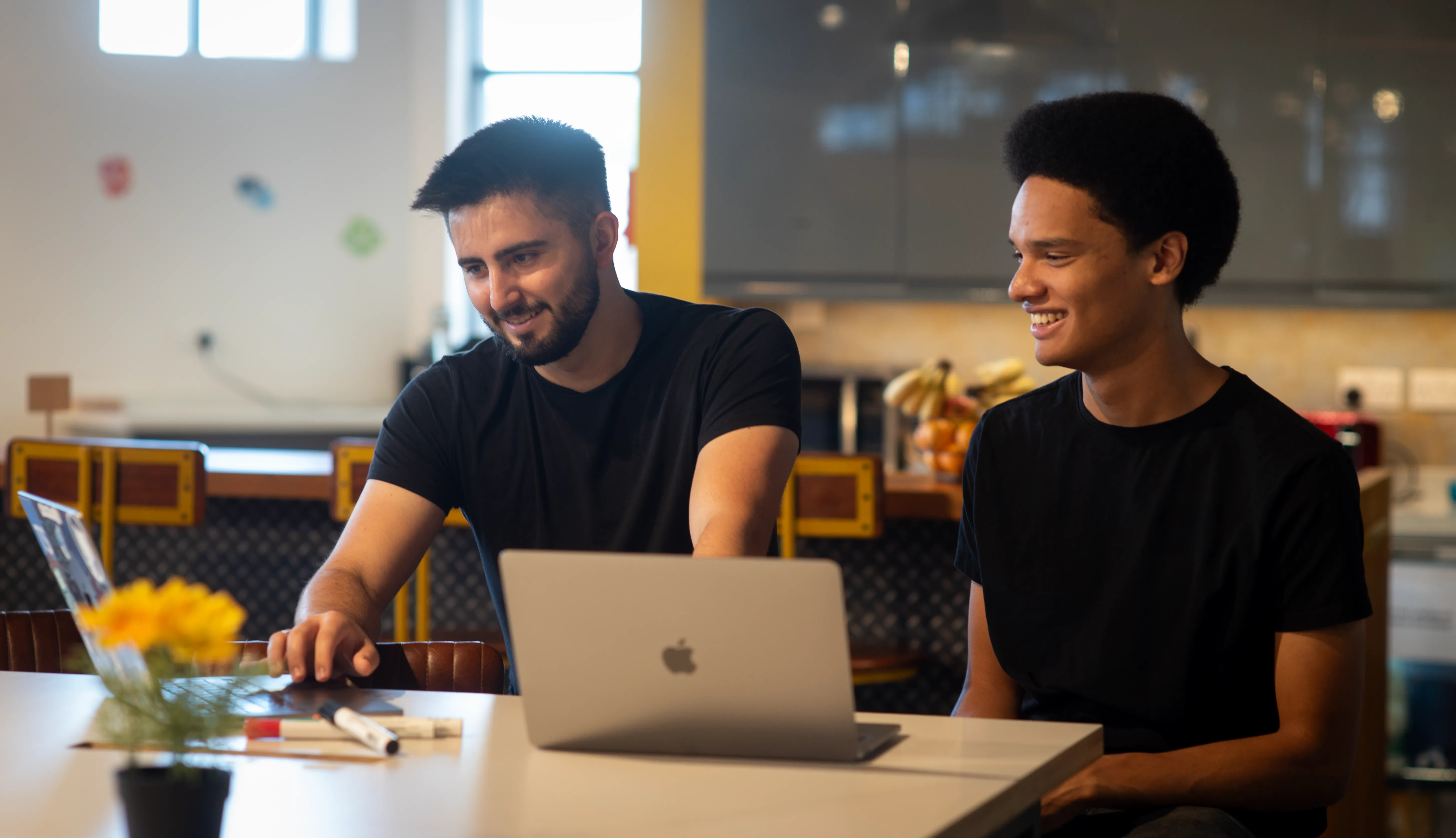 James and Niall from Novatura smiling while planning a project together on a laptop